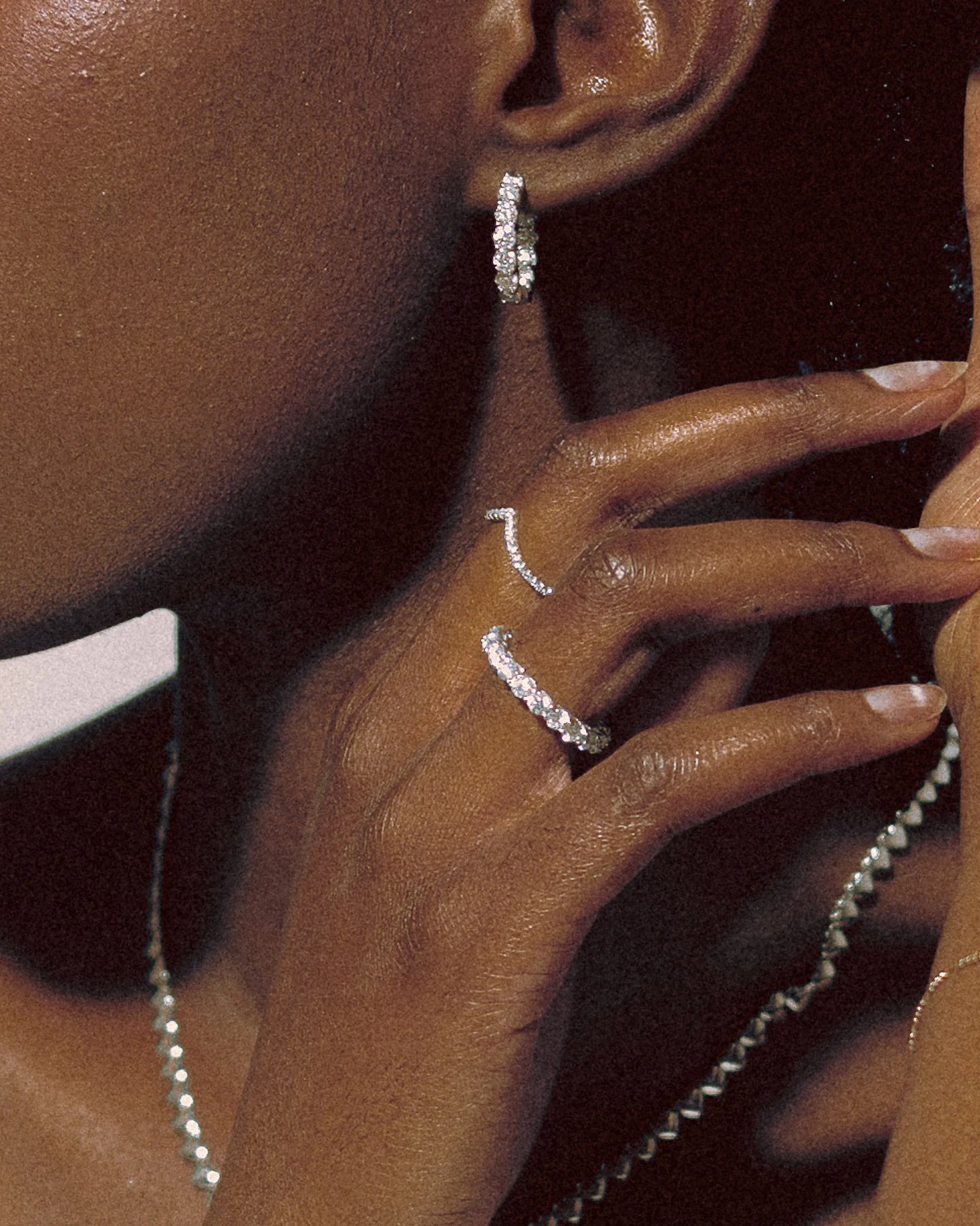 Close-up of model wearing Goldmacher Lynx and Ethereal moissanite rings, Heaven Hoop earrings, and Heart String necklace in sterling silver