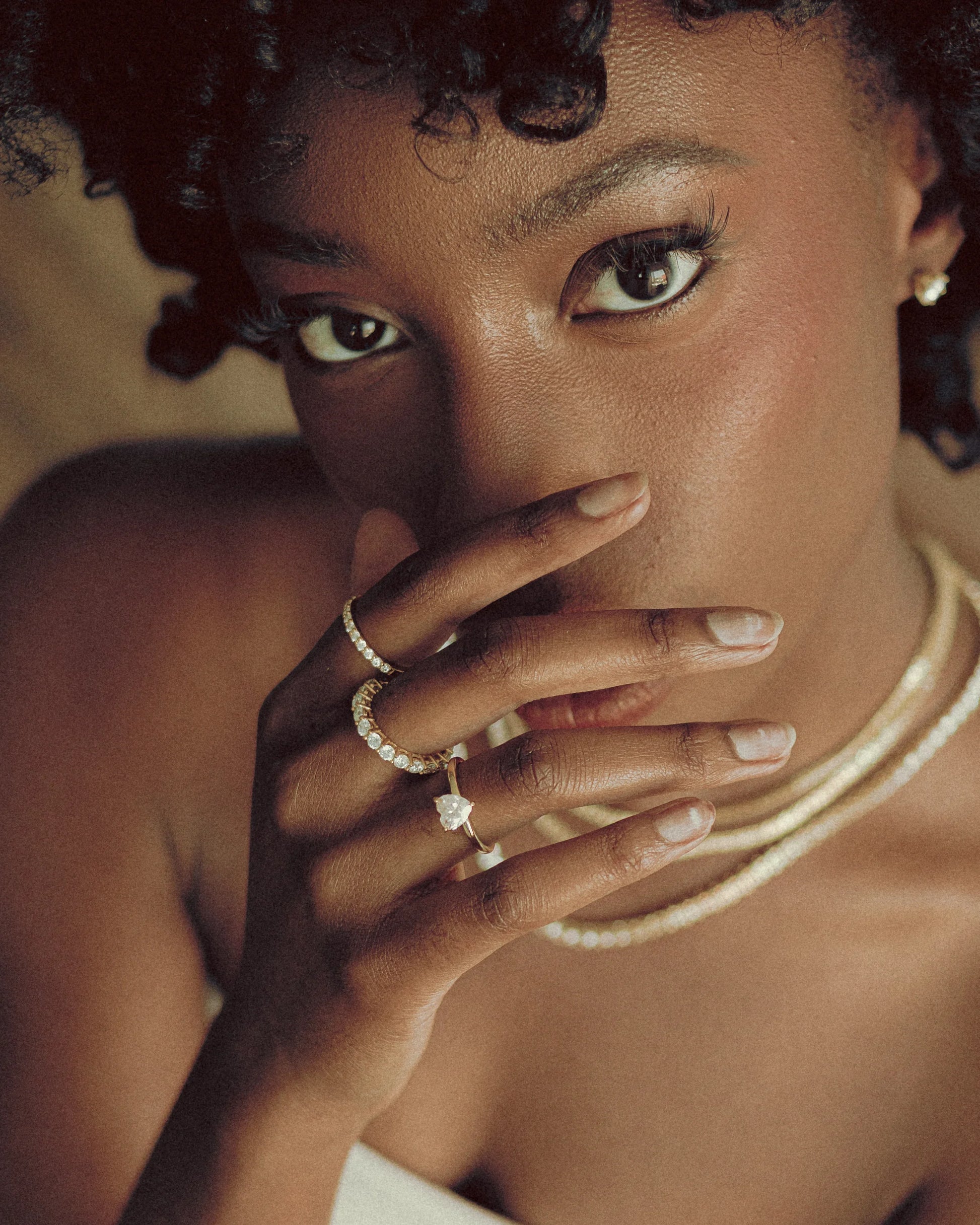 Model showcasing Goldmacher Mensa, Ethereal, and Elora 1CT moissanite rings with layered chain necklaces