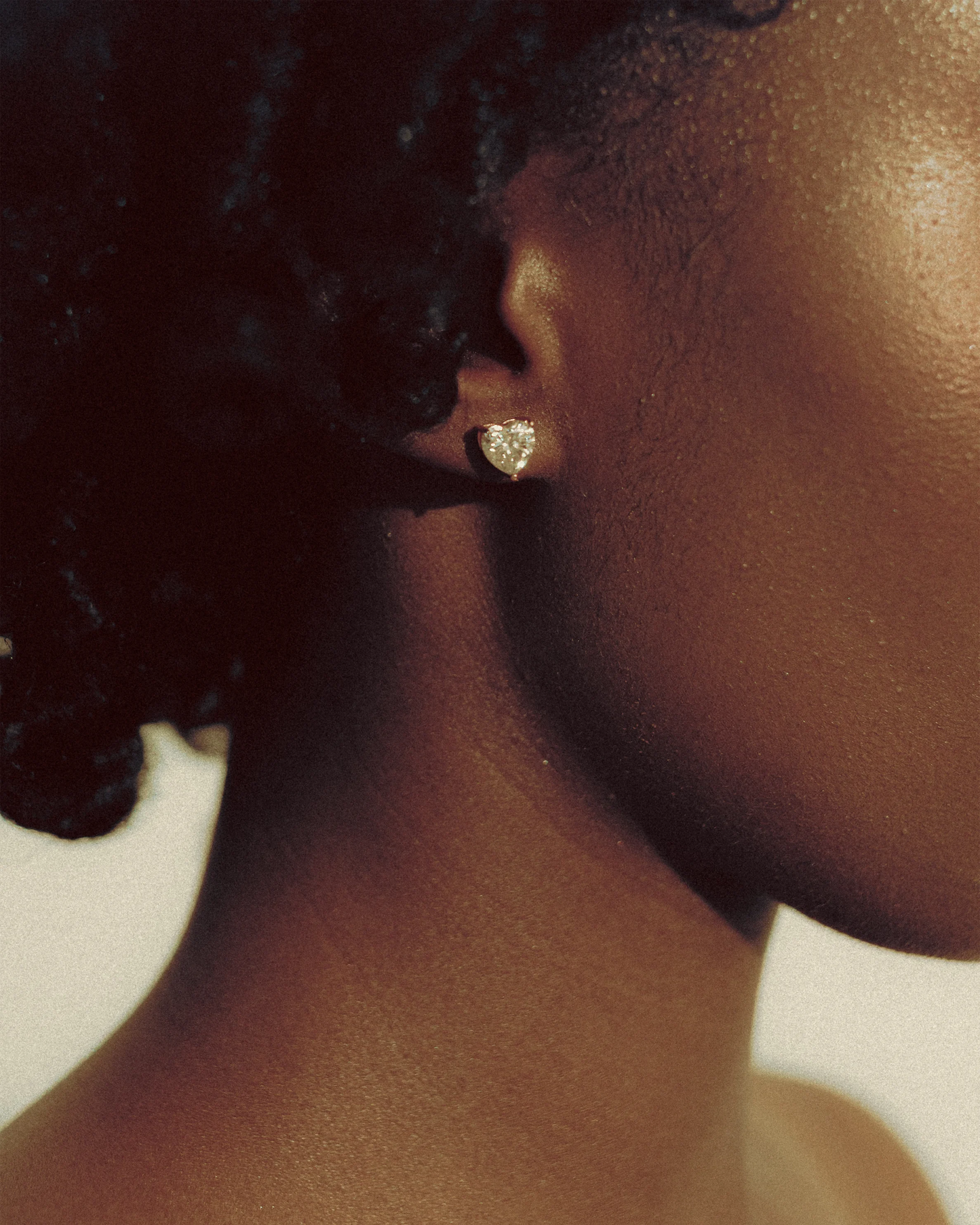 Profile shot highlighting the model’s Goldmacher moissanite heart stud earrings
