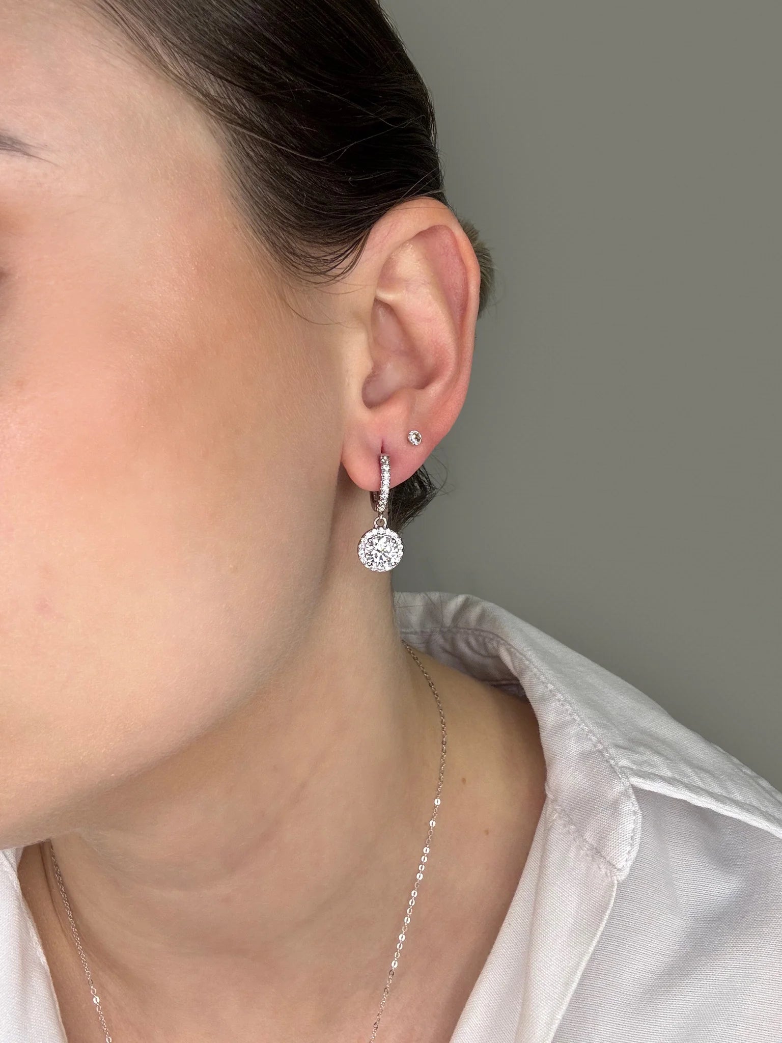 Close-up on the model’s ear, showing Goldmacher moissanite halo drop earrings