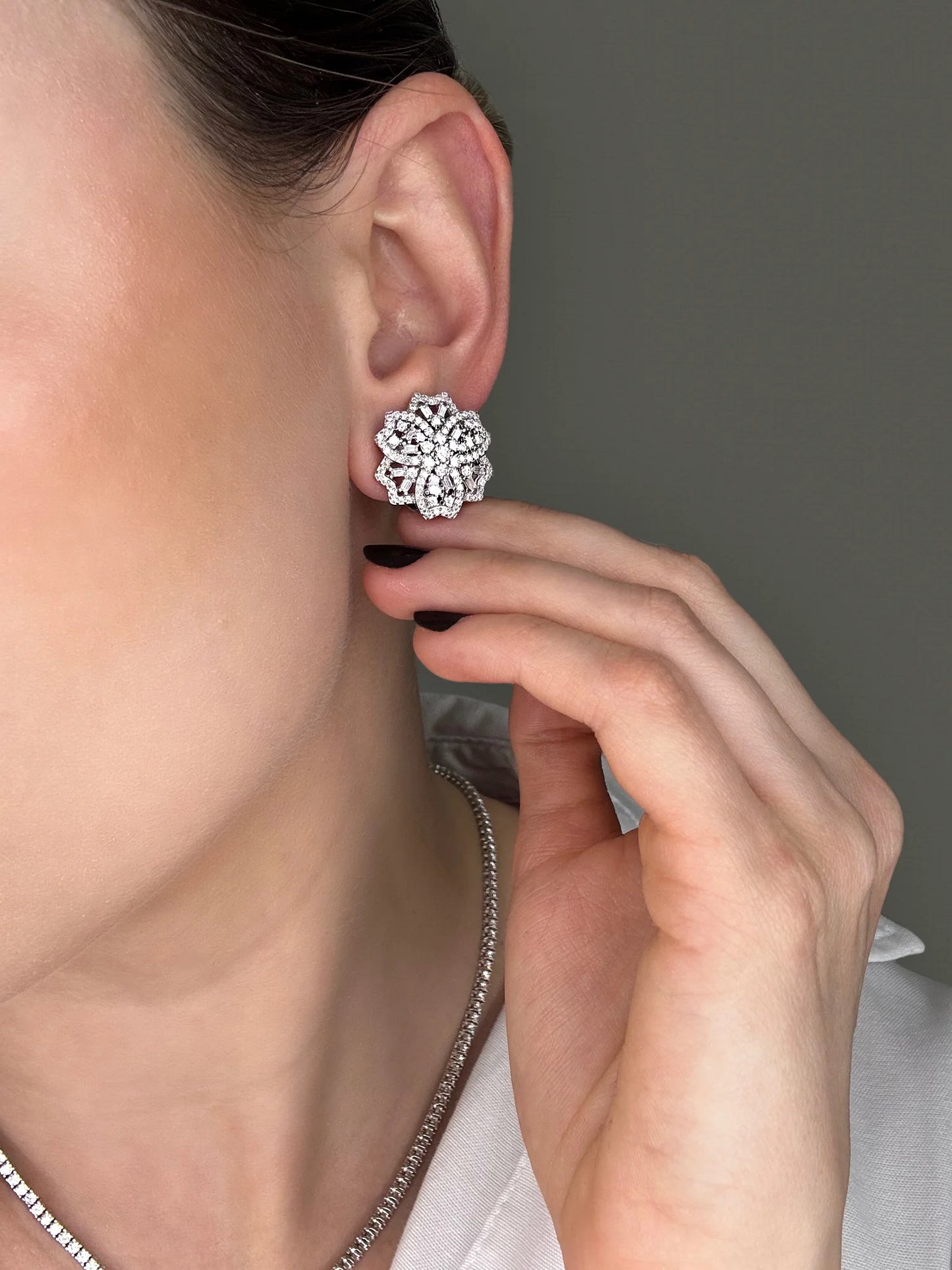 Brightly lit shot of the model wearing Goldmacher moissanite tennis chain and floral earrings