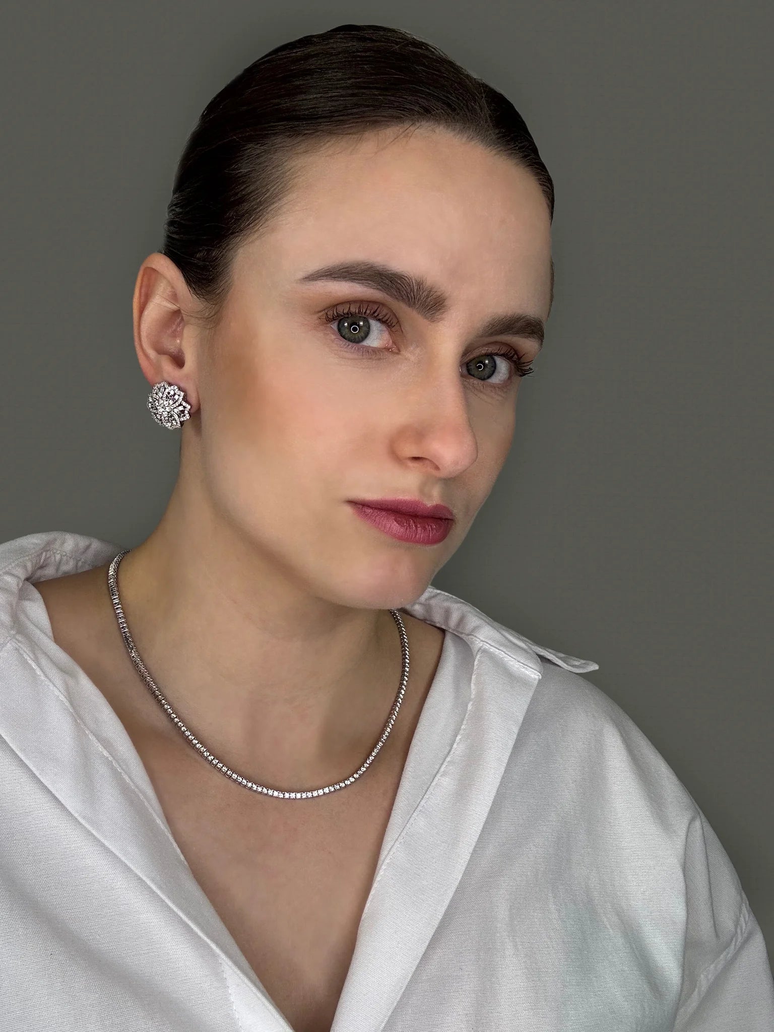 Lifestyle shot of the model blending Goldmacher moissanite floral earrings with a tennis chain necklace