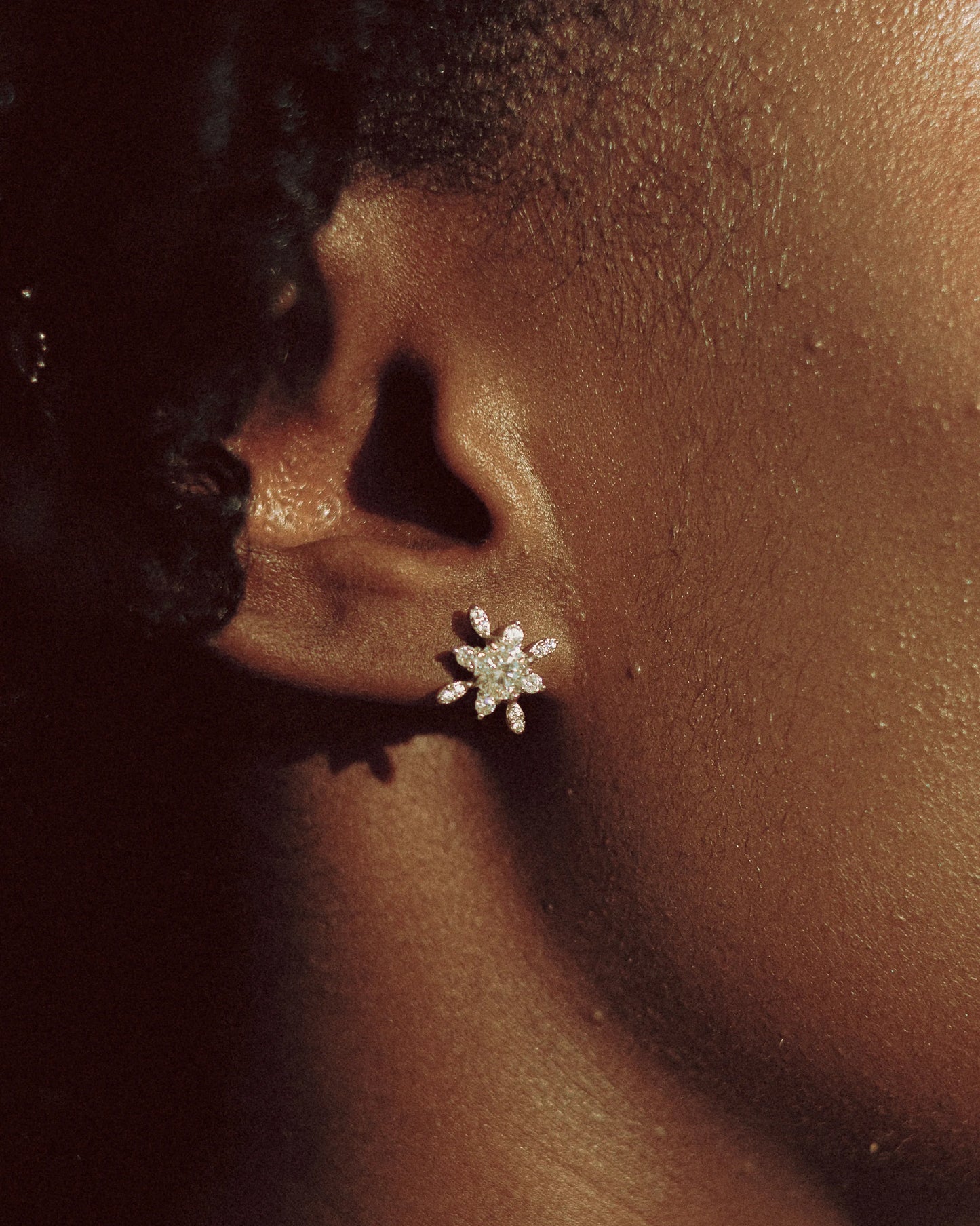 Close-up of the Goldmacher Vega 925 silver star-shaped moissanite stud earrings on the model