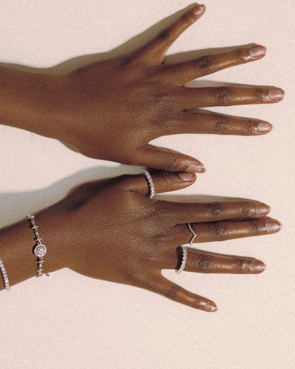 Top view of model’s hands showcasing Goldmacher Ethereal and Lynx moissanite rings, paired with Lyric and Celeste tennis bracelets in sterling silver