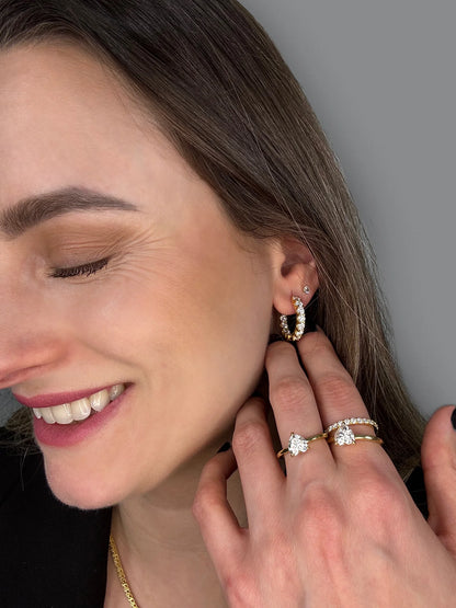 Profile angle highlighting the sparkle of Goldmacher moissanite hoop earrings and a tennis chain, with diverse ring shapes