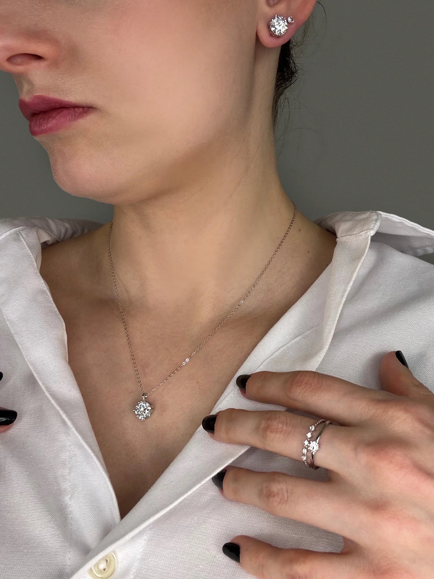 Model showcasing Goldmacher moissanite stacking rings, a simple pendant necklace, and stud earrings