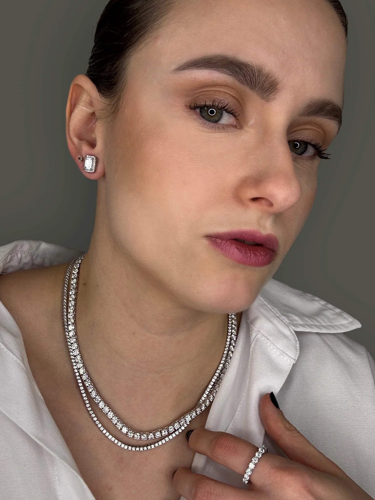 Elegantly layered look with a Goldmacher moissanite tennis chain, halo stud earrings, and eternity ring