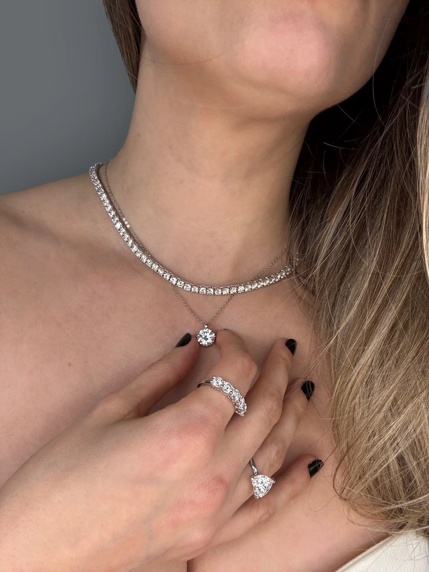 Model showcases Goldmacher moissanite tennis necklace and heart solitaire studs 2