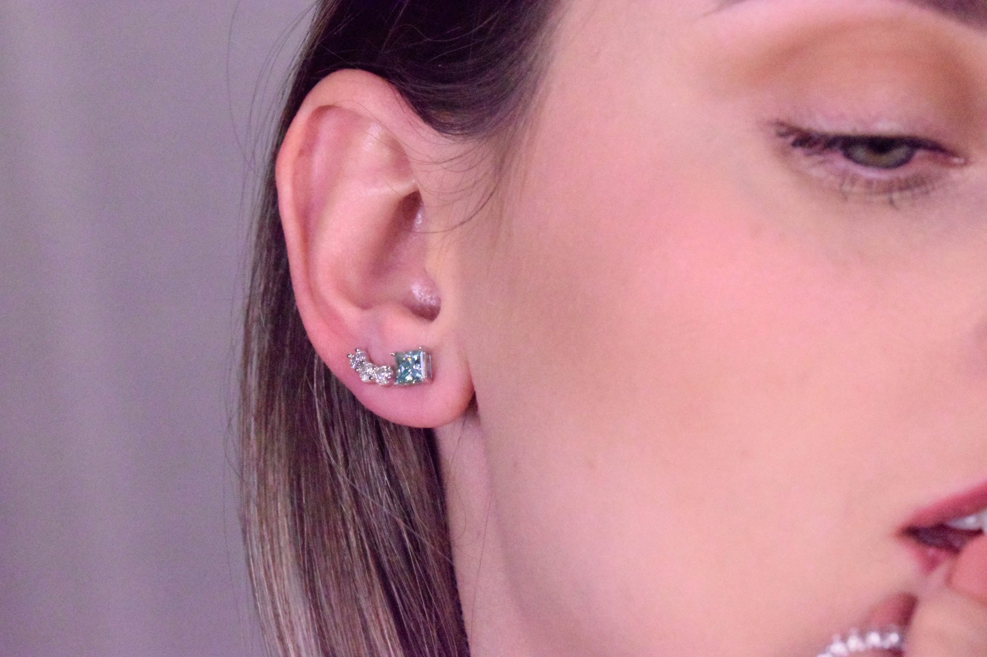 Close-up of the Goldmacher Orio 925 silver curved moissanite ear climber earrings on the model's ear