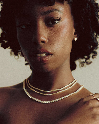  Model wearing layered Goldmacher moissanite tennis chains in gold, silver, and rose finishes for a clean stacked look
