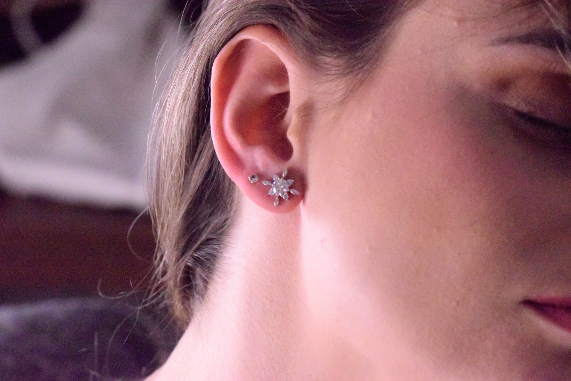 Close-up of the Goldmacher Vega 925 silver star-shaped moissanite stud earrings on the model